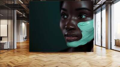 Dark-haired woman relaxes with eyes closed while applying light green face cream in a dark blue studio setting, highlighting her skin tone and intimate atmosphere. Wall mural