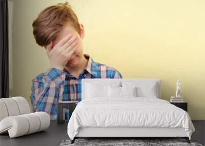 facepalm. shame and embarrassment concept. confused boy covering his face over yellow background, advertisement, banner or poster template, emotion facial expression, people reaction Wall mural