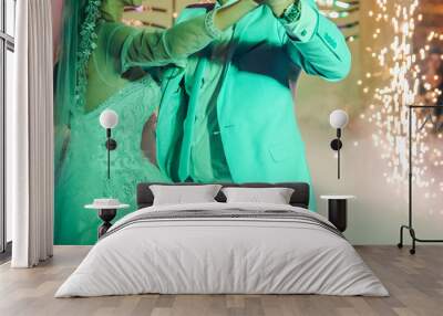 First wedding dance of a couple. Beautiful lights and luxury dress. Bride and groom in love hugging. Wall mural