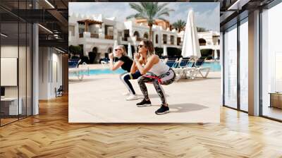 two young sports girls doing exercises with elastic,sportswoman portrait,stretch elastic squats Wall mural