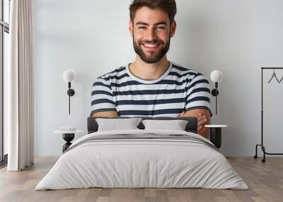 Young handsome man with beard wearing striped t-shirt standing on white background. Happy face smiling with crossed arms looking at the camera. Positive person with confident expression. Wall mural