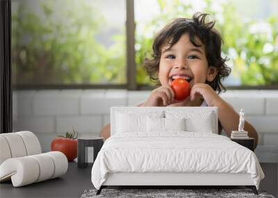 Young hispanic kid sits on table eating fresh tomato with happy face. She stands, smiles confidently showing teeth. Casual attire, long hair, brick wall background. Fresh organic fruit, vegetables. Wall mural