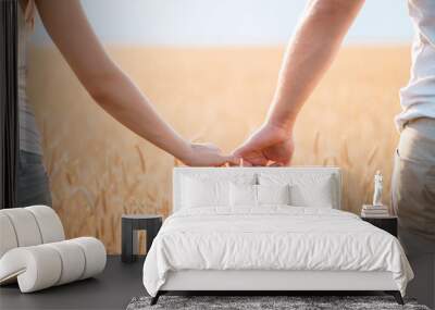 Young married couple holding hands in the sunset field background. Woman and man in love holding hearts. Human relationships and romance Wall mural