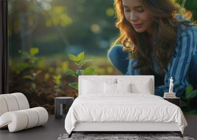 A woman planting a tree seedling in a garden warm natural lighting Wall mural