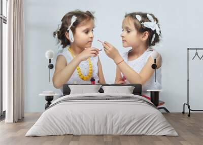 two little girls play with their mother's makeup. they pose and try to be adults.Studio, white background Wall mural