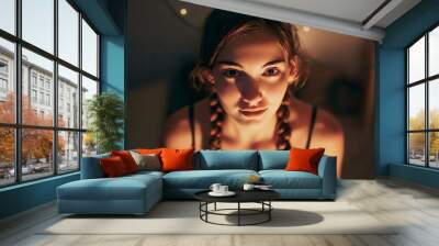 Portrait of a cute teenage girl with brown hair and braids looking at camera. A teenager in her room at night with a seductive smile and captivating gaze. Wall mural