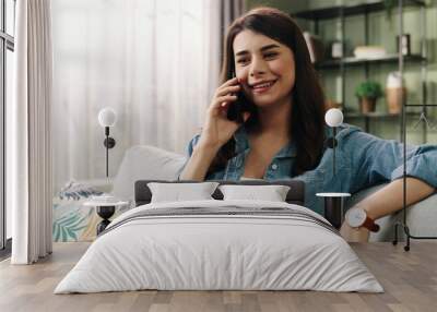 Close up of Caucasian beautiful young joyful smiling woman speaking on cellphone having conversation in positive mood calling on mobile phone while resting in room at home with happy face Call concept Wall mural