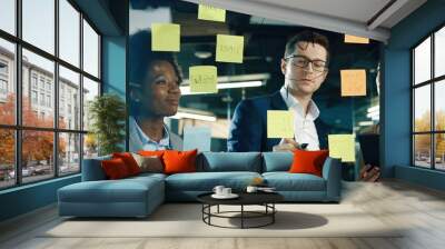 Close up of mixed-races male and female professional workers working in modern office. Handsome male manger writing on glass in cabinet while speaking with female colleagues. Work concept Wall mural