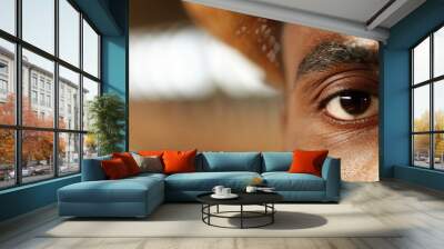 Close up of young half face of handsome African American man in hat looking straight at camera. Portrait shot of male worker. Indoor. Close-up of eye. Wall mural