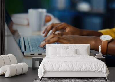 Close up shot of African American female hands typing on laptop while sitting at office desk indoors. Woman fingers tapping and texting on computer keyboard while working in cabinet. Work concept Wall mural