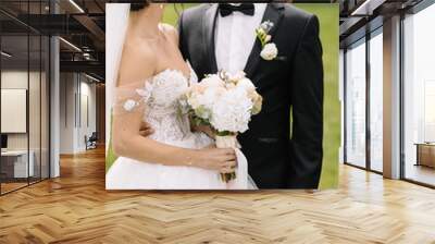 Confident elegant groom and beautiful shy bride holding hands ou Wall mural