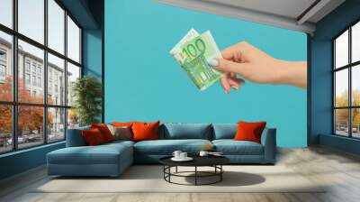 Female hands holding euro banknotes on a blue background. Wall mural