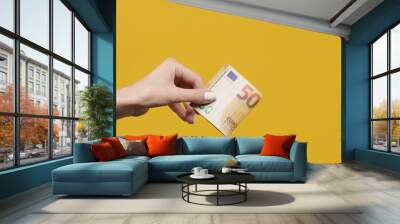 Female hands holding euro banknotes on a yellow background. Euro Money in woman hand. Euro cash background Wall mural