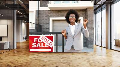 Happy young African American beautiful female real-estate agent dancing and having fun at suburb street at sold dwelling. Successful job. Cheerful businesswoman buying house. New home. Wall mural