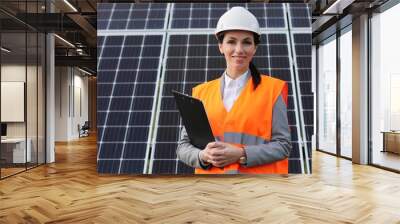 Portrait of female engineer on background field of photovoltaic solar panels. Woman technician at solar station. Wall mural