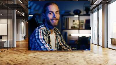 Portrait of professional video editor editing video on his personal computer with two displays in modern video studio. Young man works with headphones Wall mural