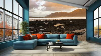 Soft sunlight coming through clouds over Lanzarote mountains with black volcanic rock Wall mural