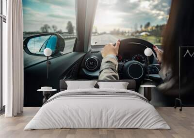 Young beautiful female driving an automobile on a highway . Wall mural