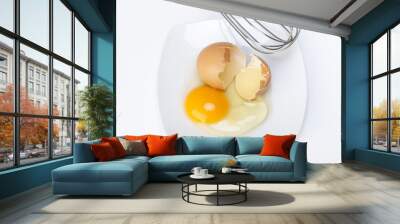 broken raw egg and wire mixing in a porcelain dish on a white Wall mural