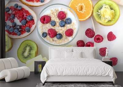 Top view, bowl of oatmeal with milk and lots of colorful fruits and berries isolated on white background Wall mural