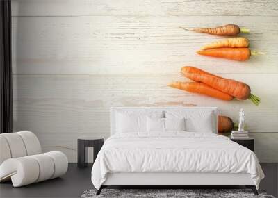 Ugly carrots lie on a light wooden surface Wall mural