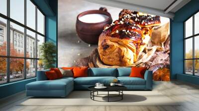 Apricot jam twisted loaf bread or babka with nuts and spices on concrete background with a cup of milk. Homemade yeast bun babka. Wall mural