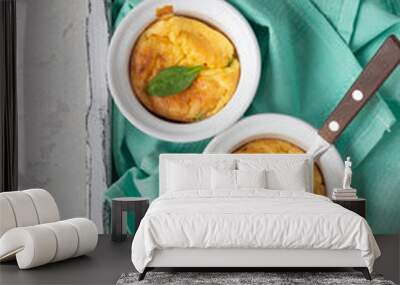 Cheese souffle with green peas in a white ceramic ramekin on a white wooden tray. Light grey concrete background. Keto diet. Comfort food. Wall mural