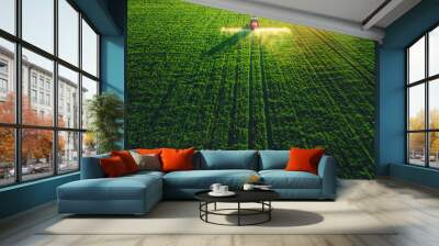 Aerial view of farming tractor plowing and spraying on field Wall mural