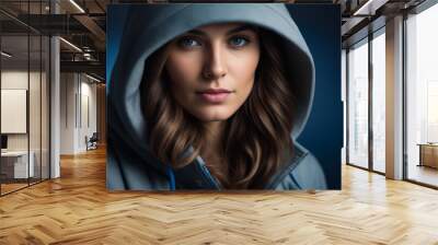 A woman with long brown hair is wearing a hooded sweatshirt and looking at the camera. The image has a moody and introspective feel to it, as the woman's gaze is directed inward Wall mural