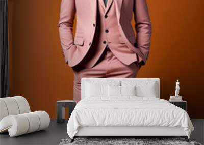 Man in pink suit and tie standing in front of brown background. Wall mural