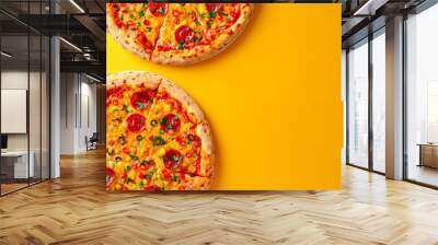 Two pizzas with pepperoni and cheese on top. The pizzas are on a yellow background Wall mural