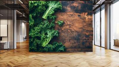 Fresh, vibrant kale leaves scattered on rustic wooden table, creating a striking contrast between lush green vegetables and rich brown wood grain texture. Wall mural