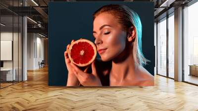  Woman with grapefruit on a gray background. Wall mural