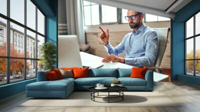 A man in a shirt and glasses is talking on a video call, an online business conference, a meeting. Freelance, work from home. Wall mural