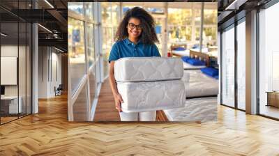 An African American woman sales assistant demonstrates samples of mattresses in a bed, mattress and pillow store. Wall mural