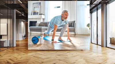 Sport, fitness and healthy lifestyle concept. Mature man doing exercises at home. How to stay healthy on quarantine concept. Wall mural