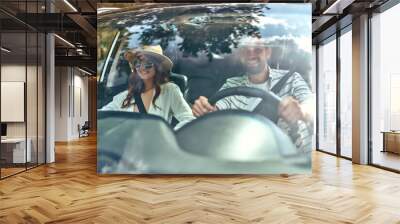 Young couple in a new car. A man driving a car with his girlfriend and having fun. Buying and renting a car. Travel, tourism, recreation. Wall mural