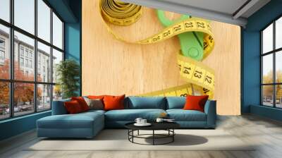 Yellow measuring tape with scissors on wooden background Wall mural