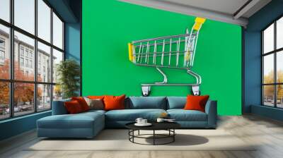 Yellow shopping cart or trolley on green background  Wall mural