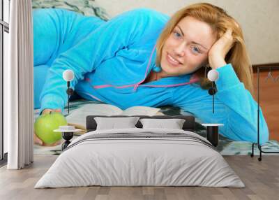 Young woman reading book on sofa Wall mural