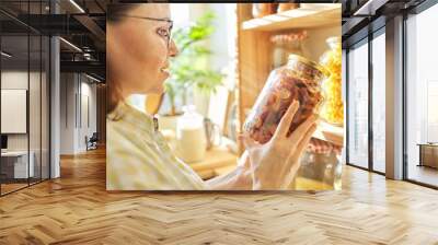 Food storage in pantry, woman holding jar of dry sun-dried apples in hand. Wall mural