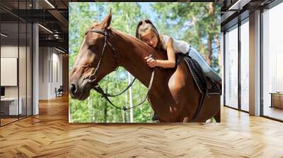 Girl child riding horse, summer horse ride in the forest, girl lovingly hugged horse Wall mural