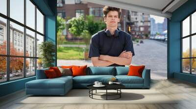 Handsome young man looking at camera outdoors, city street background Wall mural