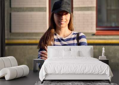 Outdoor portrait of teenage girl in black cap, city street background Wall mural