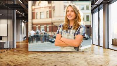 Outdoor portrait of teenager 13, 14 years old, girl with crossed arms, city street background Wall mural