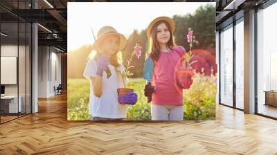 Portrait of two little gardeners in gloves with flowering plants in pots and garden shovels Wall mural