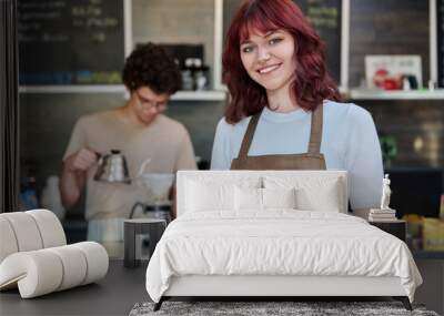 Portrait of young female waitress in front of counter in coffee shop Wall mural