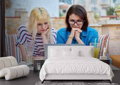 Sad upset serious mom and teenage daughter looking together into a laptop screen. Wall mural