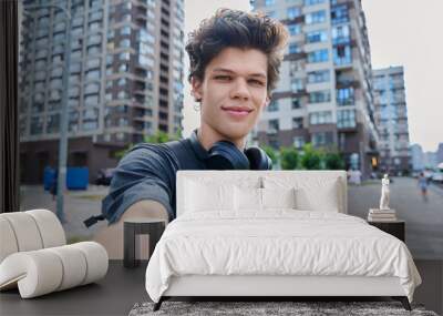 Selfie portrait of young handsome man with curly hair, outdoor Wall mural