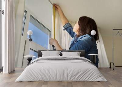 Service for sewing and hanging curtains. Woman with tape measure measuring window Wall mural